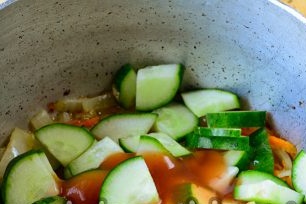 tambah timun dan pes tomato ke dalam kuali dengan bawang dan wortel