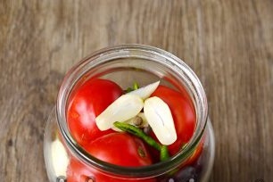 giet de pot infusie en voeg knoflook toe aan de tomaten