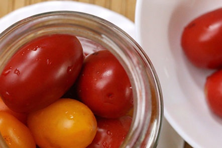 putting tomatoes in a jar